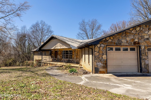 view of front of home featuring covered porch, stone siding, concrete driveway, and an attached garage