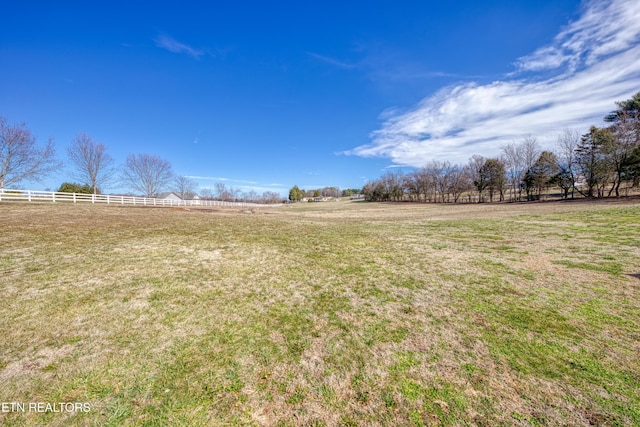 view of yard with fence and a rural view