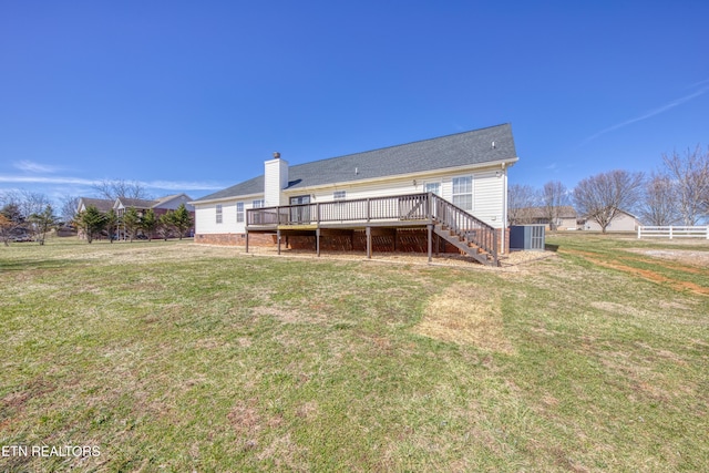 rear view of house featuring a chimney, a lawn, fence, a wooden deck, and stairs