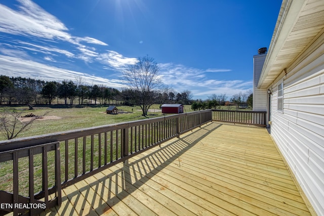 wooden terrace with a storage unit, a lawn, and an outbuilding