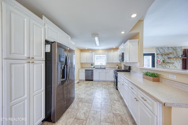 kitchen featuring appliances with stainless steel finishes, light countertops, white cabinets, and a healthy amount of sunlight