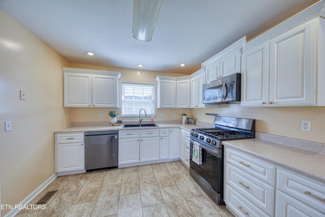 kitchen with visible vents, white cabinets, stainless steel appliances, light countertops, and a sink