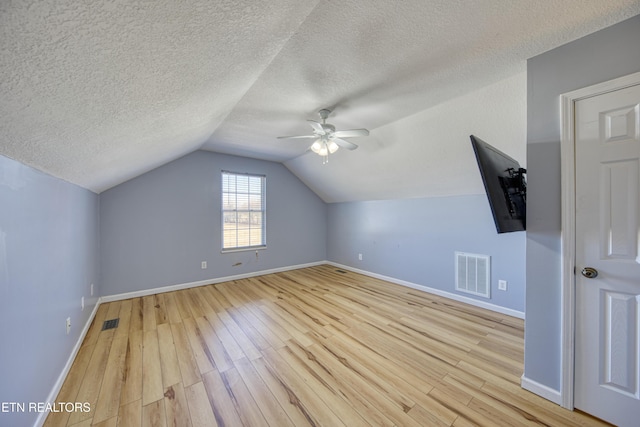 additional living space featuring baseboards, visible vents, vaulted ceiling, and light wood finished floors