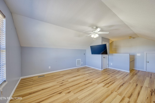 additional living space featuring baseboards, visible vents, vaulted ceiling, and wood finished floors