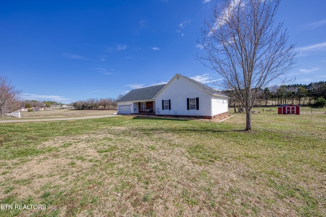 view of front of house featuring a garage, driveway, a front lawn, and a storage unit