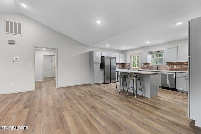 kitchen with stainless steel appliances, light countertops, visible vents, a sink, and a kitchen breakfast bar