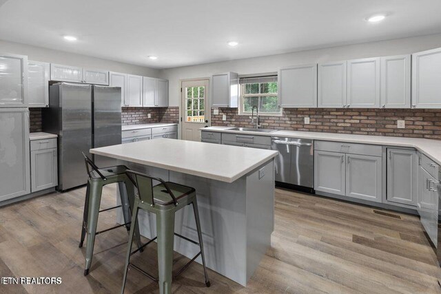 kitchen with appliances with stainless steel finishes, a breakfast bar, light wood-style floors, and a sink