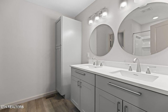 full bath with visible vents, a sink, and wood finished floors