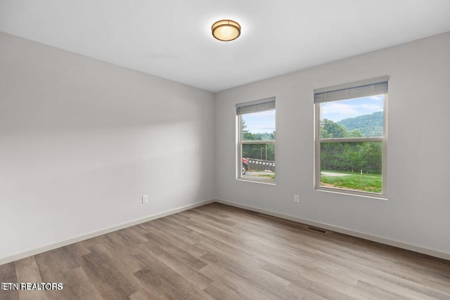 spare room with visible vents, baseboards, and wood finished floors