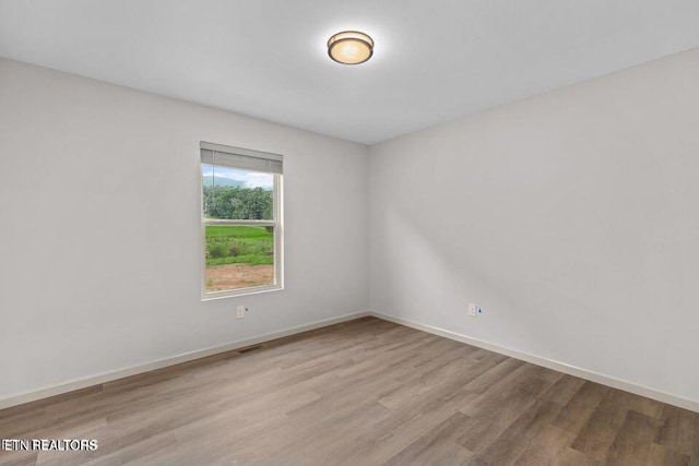 unfurnished room with visible vents, baseboards, and wood finished floors