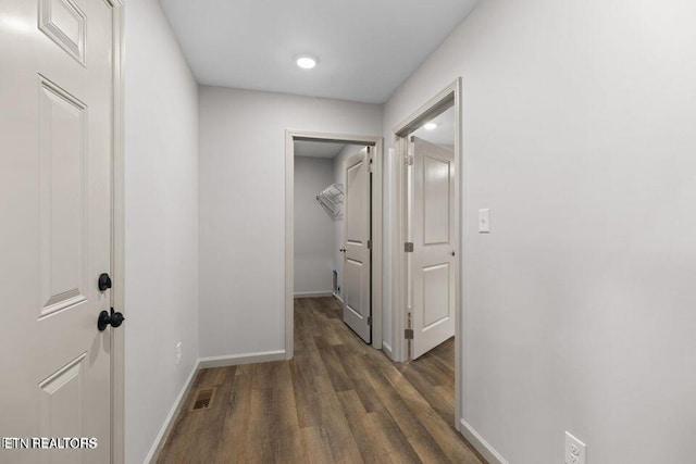 corridor featuring visible vents, baseboards, and wood finished floors