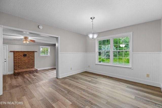 unfurnished dining area featuring visible vents, ceiling fan, a textured ceiling, and wood finished floors