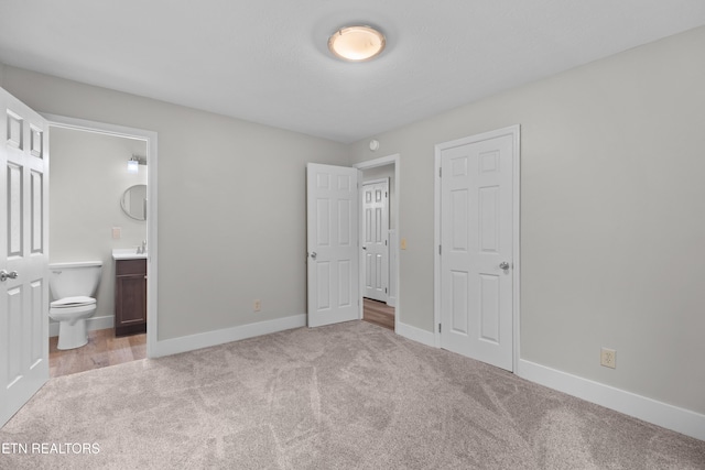 unfurnished bedroom with light carpet, ensuite bath, and baseboards