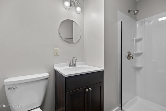 bathroom featuring toilet, a stall shower, and vanity