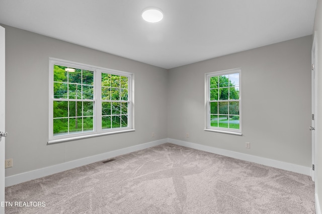 carpeted spare room featuring visible vents and baseboards