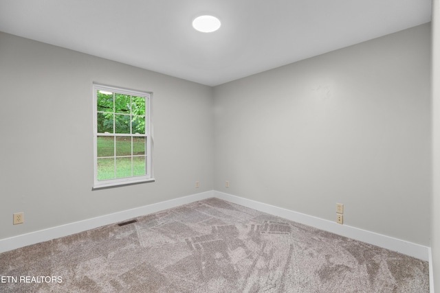 spare room with carpet, visible vents, and baseboards