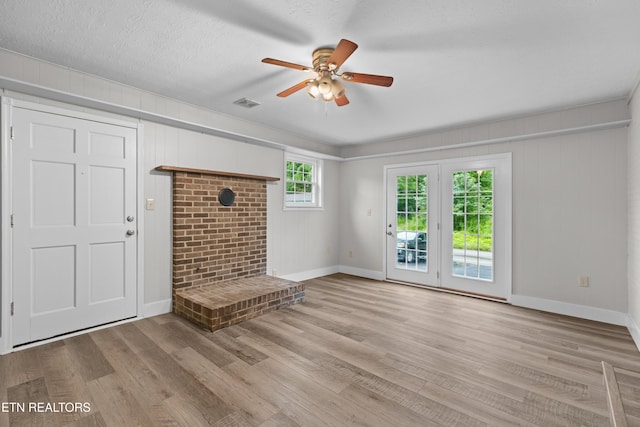 unfurnished living room featuring a textured ceiling, wood finished floors, visible vents, baseboards, and a ceiling fan