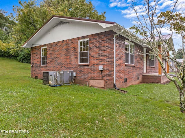 view of side of property with cooling unit, crawl space, brick siding, and a yard