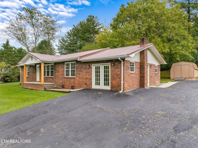 view of front of home featuring crawl space, brick siding, a chimney, and a storage shed