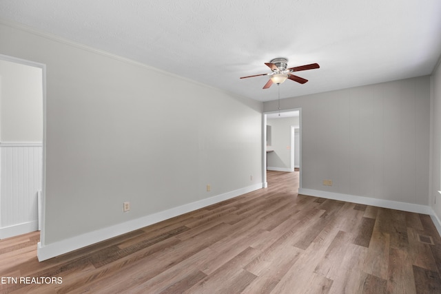 empty room featuring ceiling fan, a textured ceiling, wood finished floors, visible vents, and baseboards