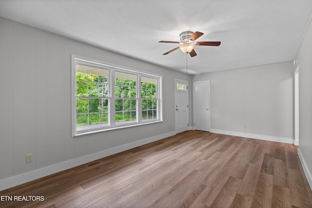 unfurnished room with visible vents, ceiling fan, a textured ceiling, wood finished floors, and baseboards