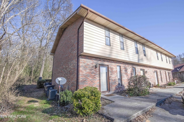 view of side of home featuring brick siding and central AC