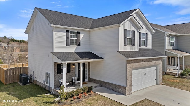 traditional home with roof with shingles, brick siding, central air condition unit, an attached garage, and fence