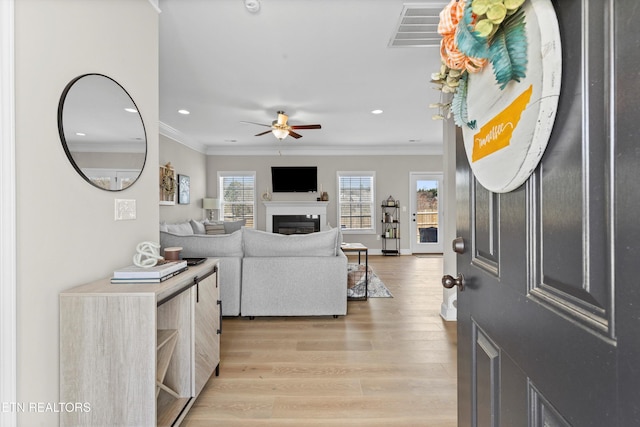 entrance foyer featuring recessed lighting, a fireplace, visible vents, ornamental molding, and light wood-type flooring