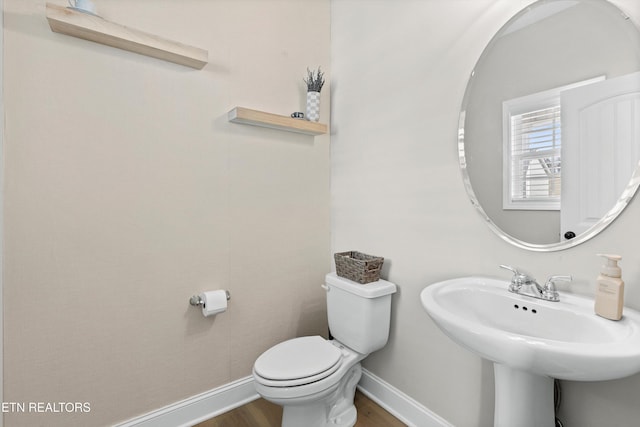 bathroom with toilet, a sink, baseboards, and wood finished floors