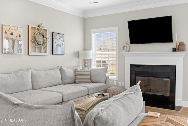 living room with a fireplace with flush hearth, visible vents, crown molding, and wood finished floors