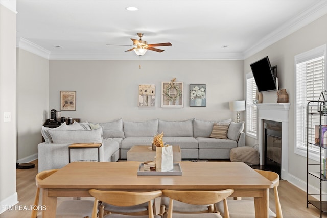 living area with light wood-style floors, crown molding, and a glass covered fireplace