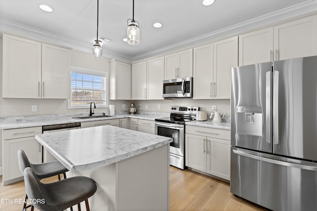 kitchen featuring a breakfast bar, hanging light fixtures, stainless steel appliances, light wood-type flooring, and a sink