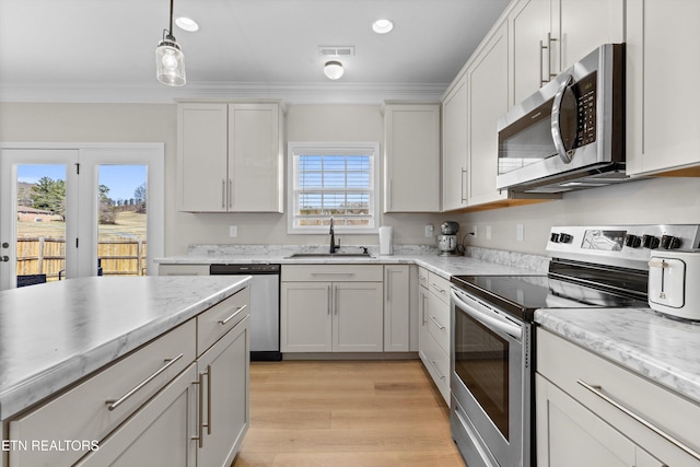 kitchen with stainless steel appliances, visible vents, a sink, and ornamental molding