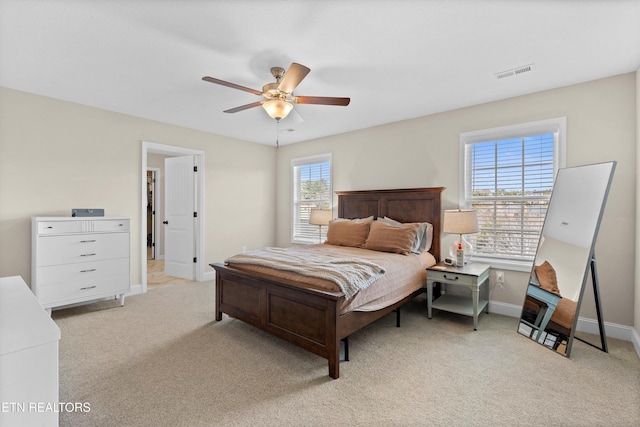 bedroom with light carpet, multiple windows, visible vents, and baseboards