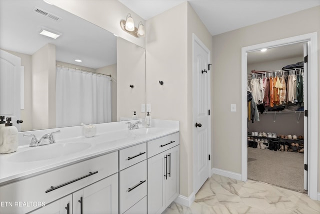 bathroom featuring marble finish floor, double vanity, a sink, and visible vents