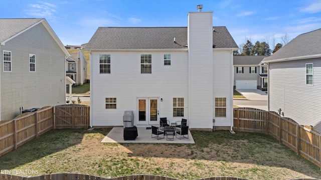 rear view of property with a gate, a fenced backyard, a patio, and a chimney