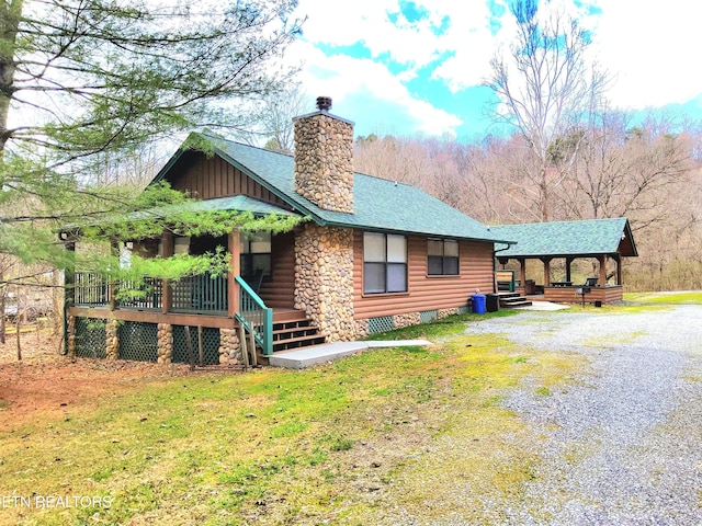 exterior space with driveway, a chimney, a porch, and roof with shingles