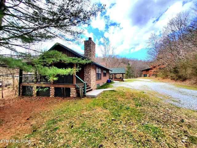 view of property exterior featuring a yard, driveway, and a chimney