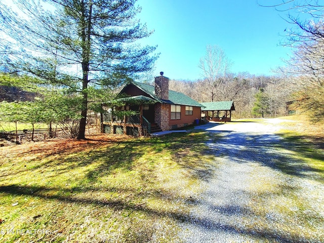 view of side of property with driveway, a yard, crawl space, and a chimney