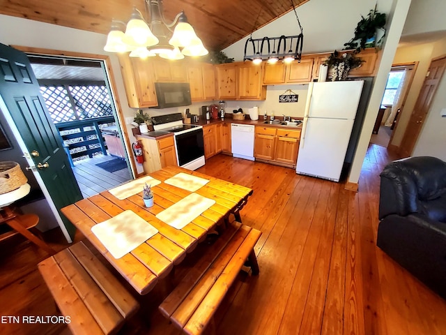 kitchen featuring white appliances, lofted ceiling, hardwood / wood-style floors, an inviting chandelier, and a sink