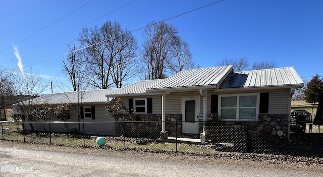 view of front of house with metal roof, stone siding, and a fenced front yard