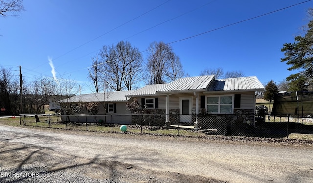 view of front of home with a fenced front yard, stone siding, and metal roof