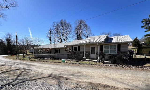 view of front facade featuring metal roof, a fenced front yard, and stone siding