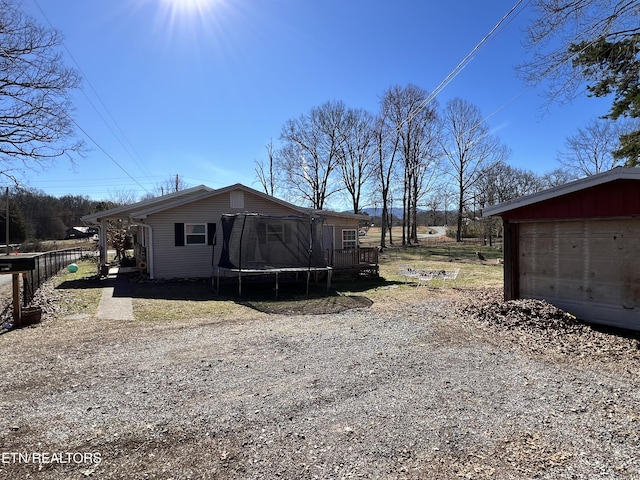 view of property exterior with a trampoline, driveway, a garage, and fence