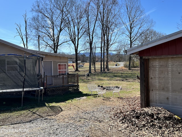 view of yard with a trampoline, fence, and an outdoor structure