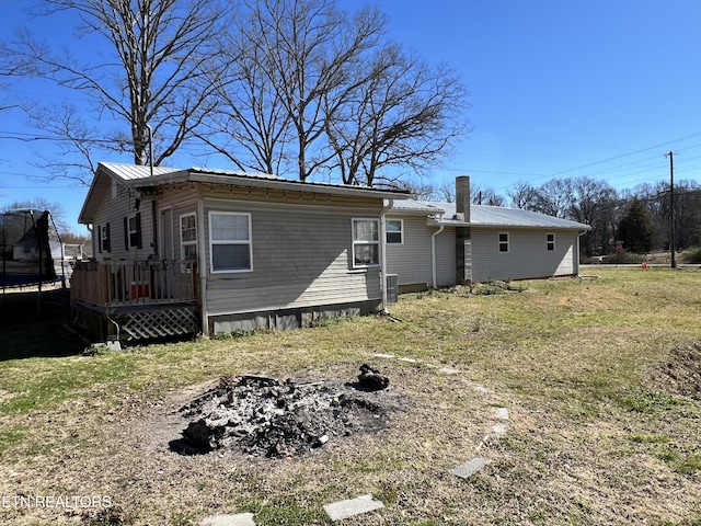 back of house featuring a fire pit, metal roof, and a trampoline