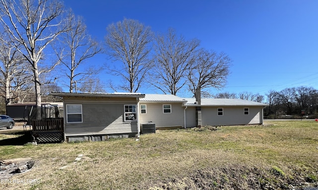 rear view of house with a yard, metal roof, and central AC unit