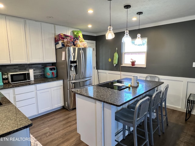 kitchen featuring white cabinets, stainless steel fridge, and a wainscoted wall