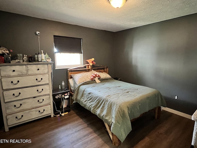 bedroom featuring dark wood finished floors, a textured ceiling, and baseboards