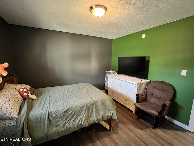 bedroom with a textured ceiling, wood finished floors, and baseboards